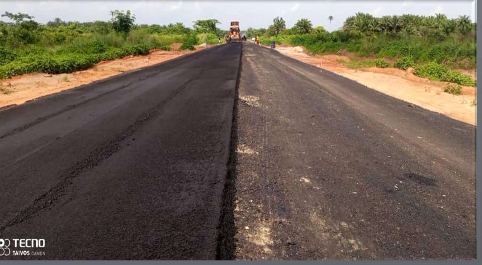 Freshly laid asphalt on the Obaretin Forest Reserve road with grass verges on both sides