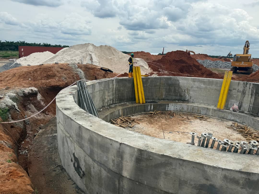 Finished tank foundation ring beside an excavator and stockpiled aggregate