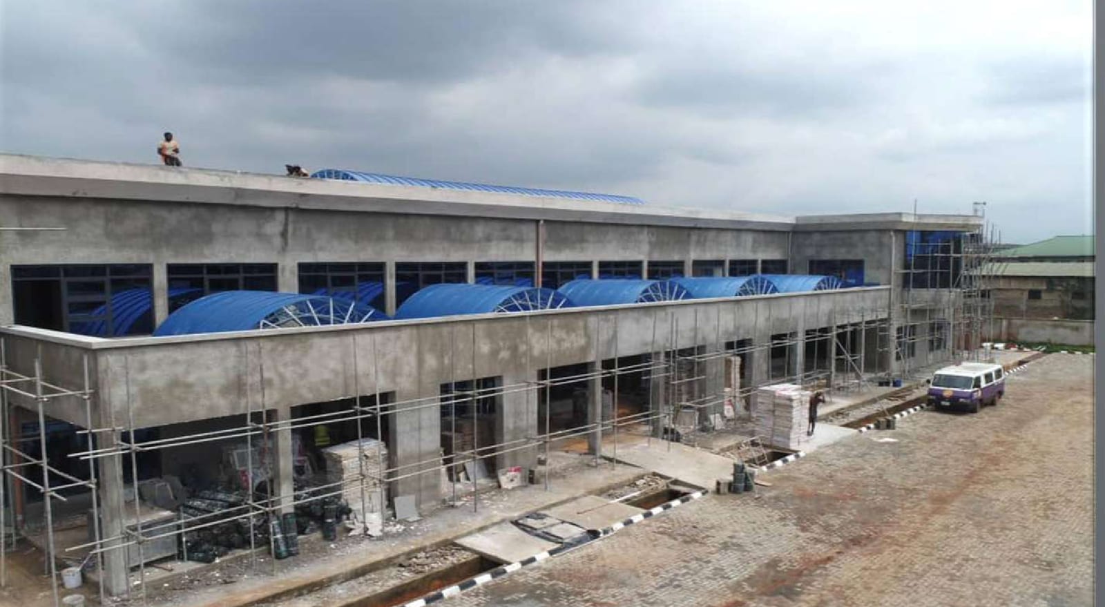 Terminal facade under construction with scaffolding and blue roof canopies