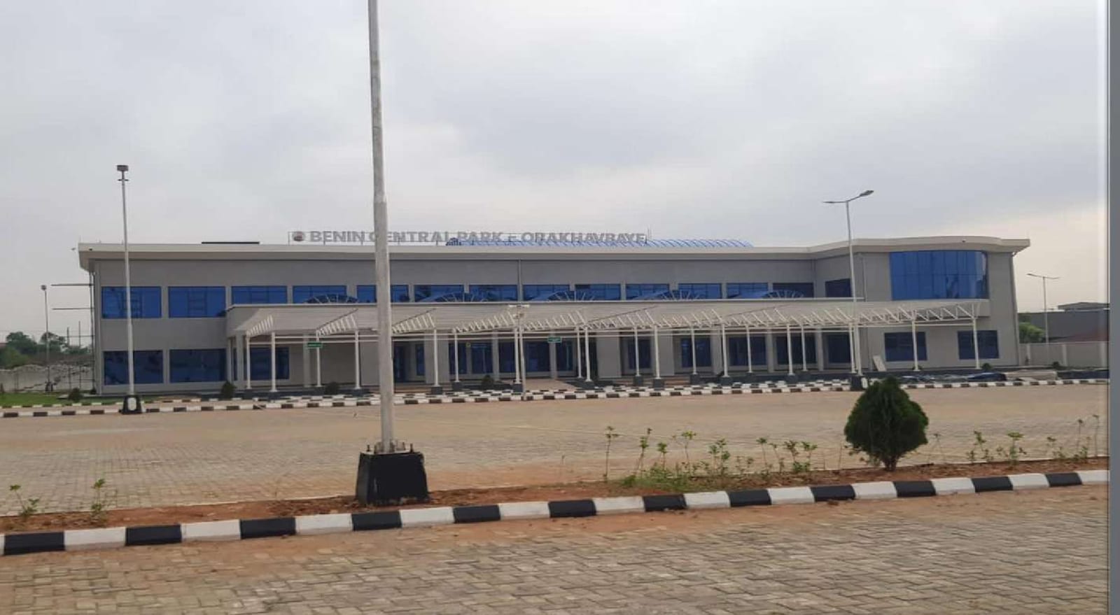 Completed Benin Central Park bus terminal building with blue-glazed facade and flagpole