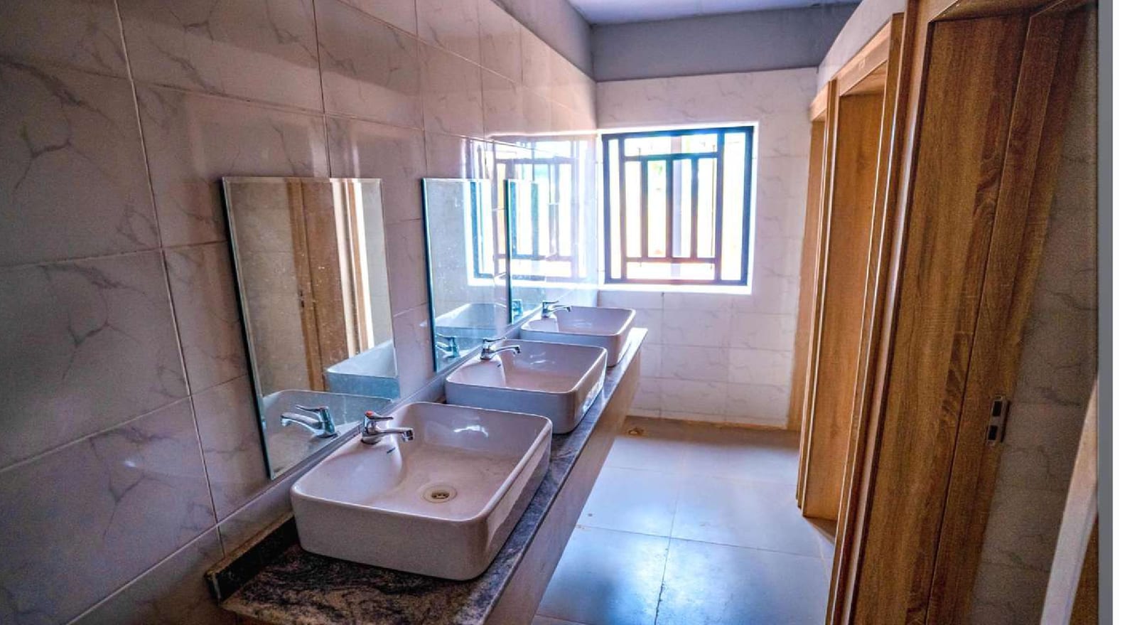Finished restroom with washbasins, mirrors and timber doors