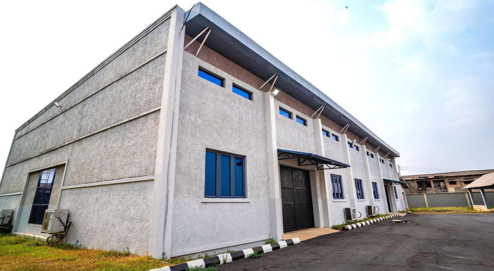Corner of the completed printing house with metal roof and blue-framed windows